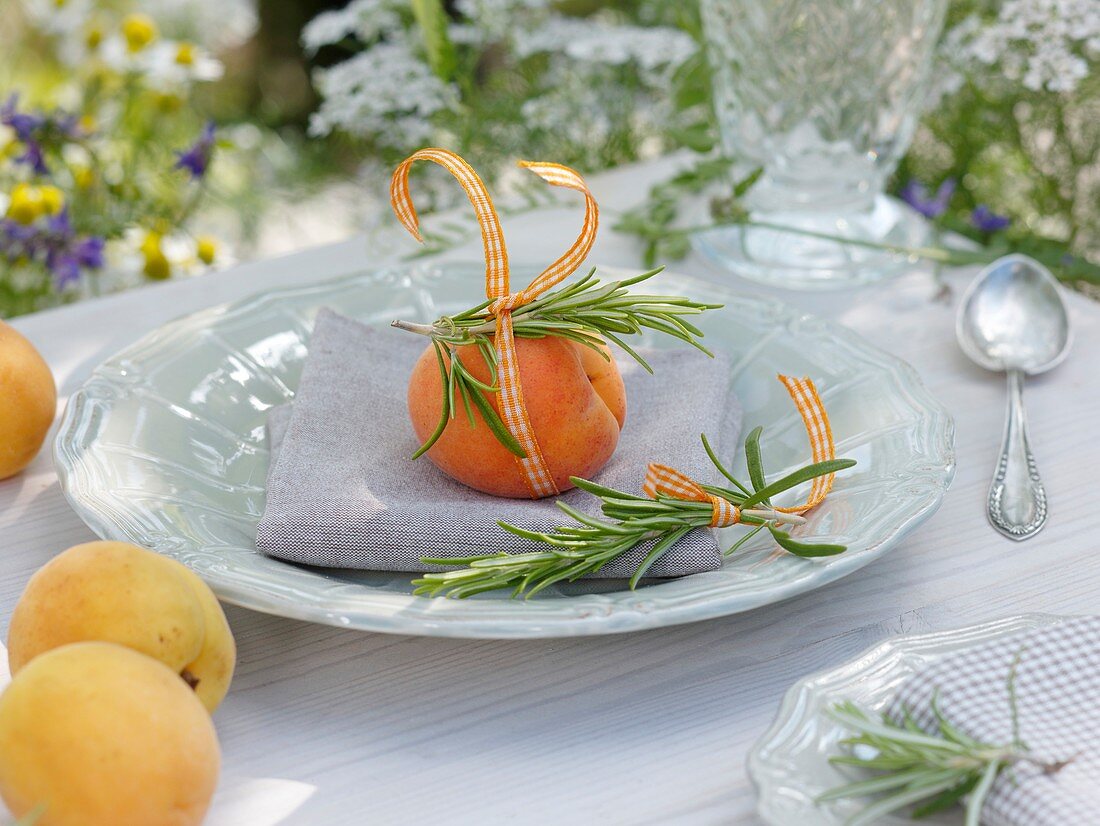 Summery place-setting with apricot and rosemary sprigs