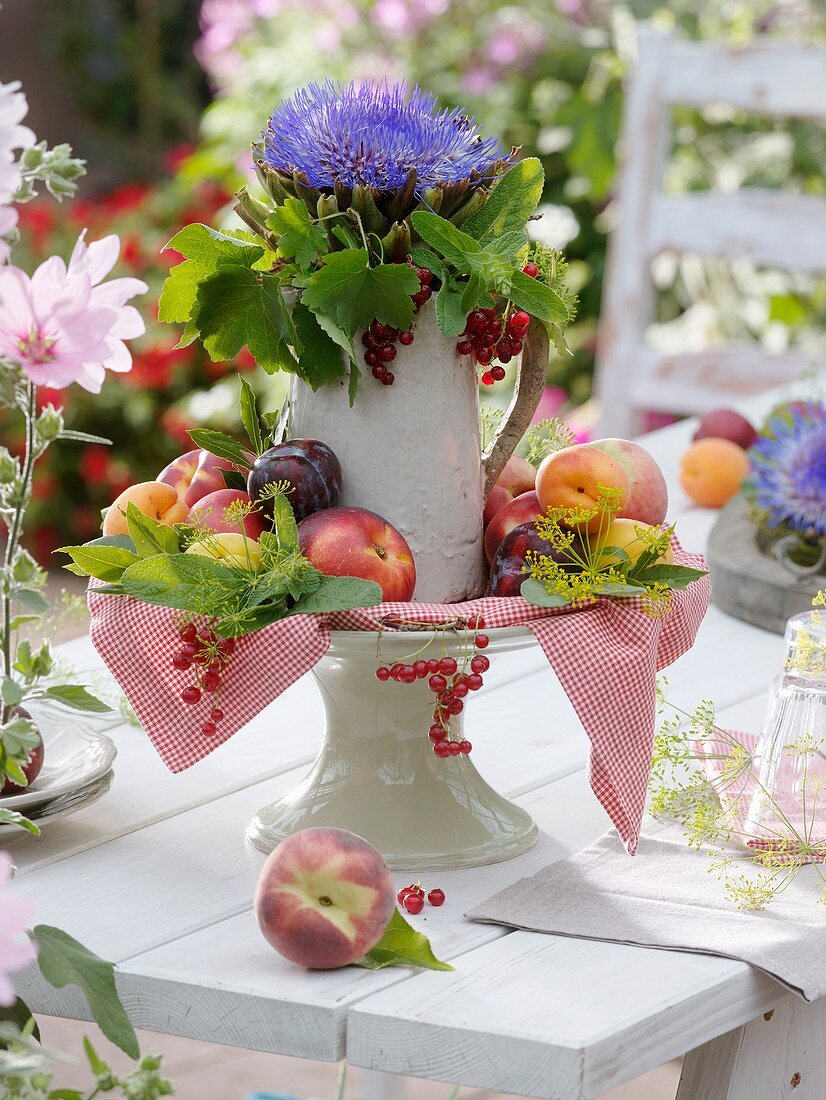 Artichoke flower with redcurrants and stone fruit on cake stand