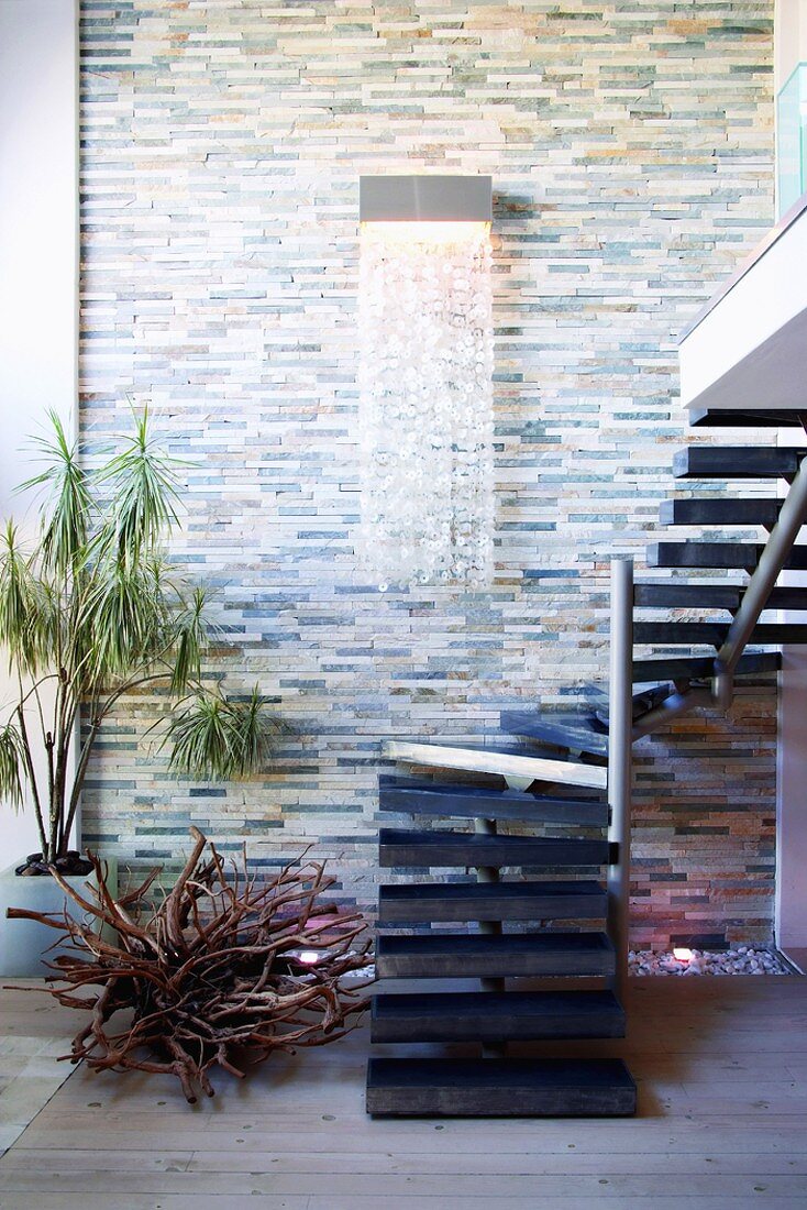 Wall lamp with shower of crystals on stone wall and winding staircase leading to gallery