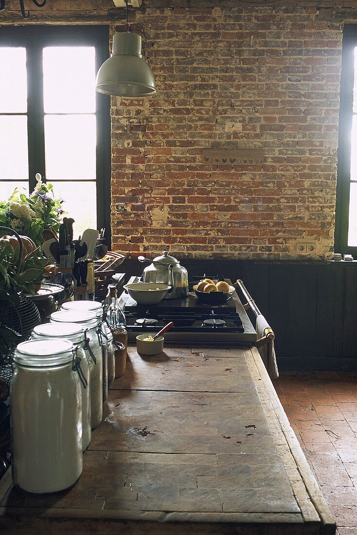 Rustic work surface, gas hob and brick wall in kitchen