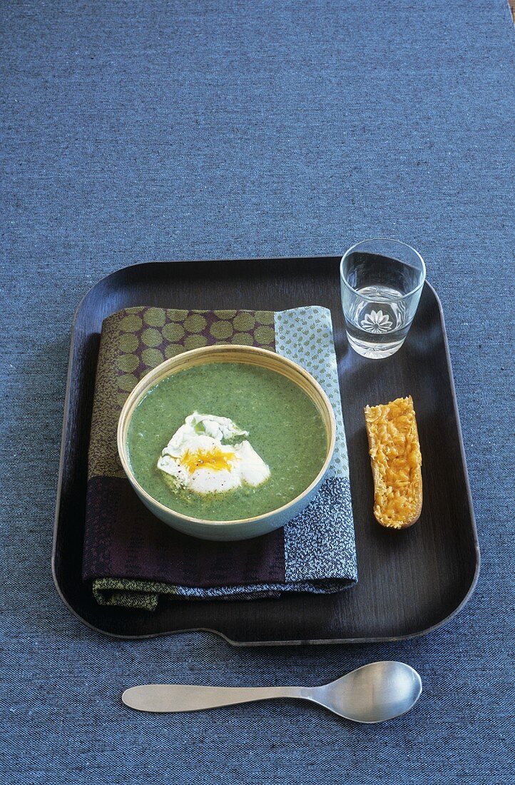 Cream of cress soup with poached egg and cheese croute on tray