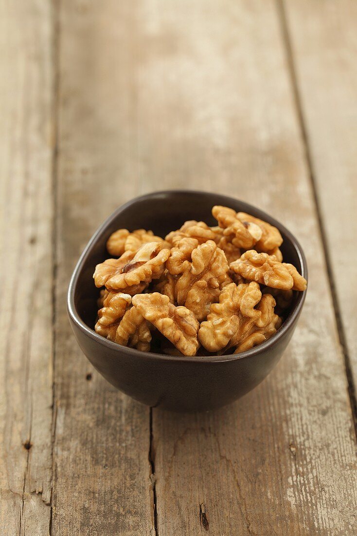 A bowl of walnuts on a wooden surface