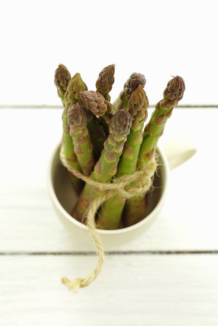 A bunch of green asparagus in a cup