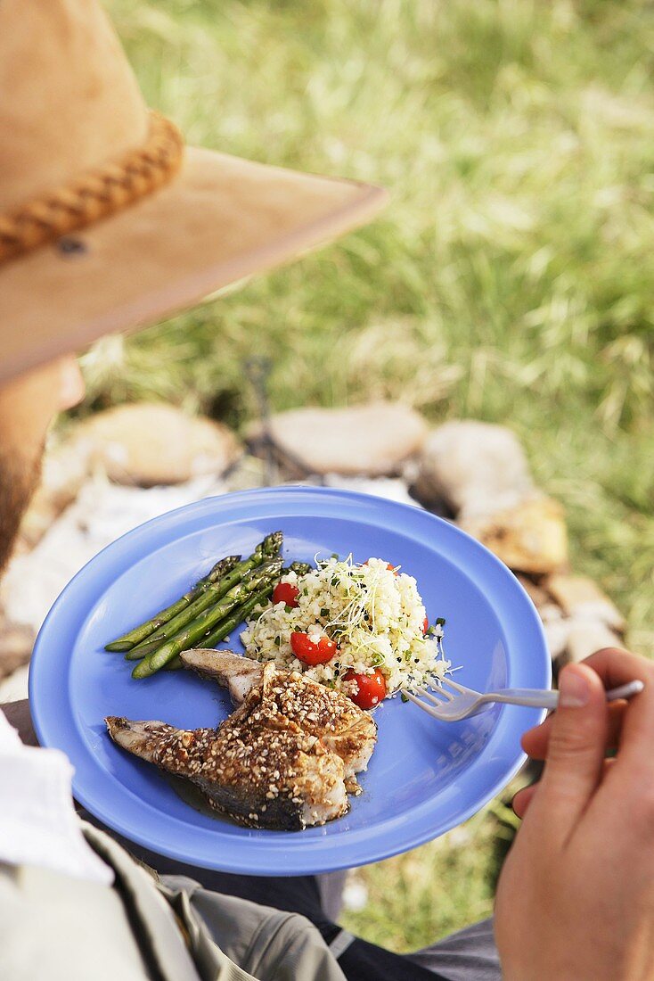 Mann isst Fisch mit Dukkah (Nuss-Gewürz-Panade)