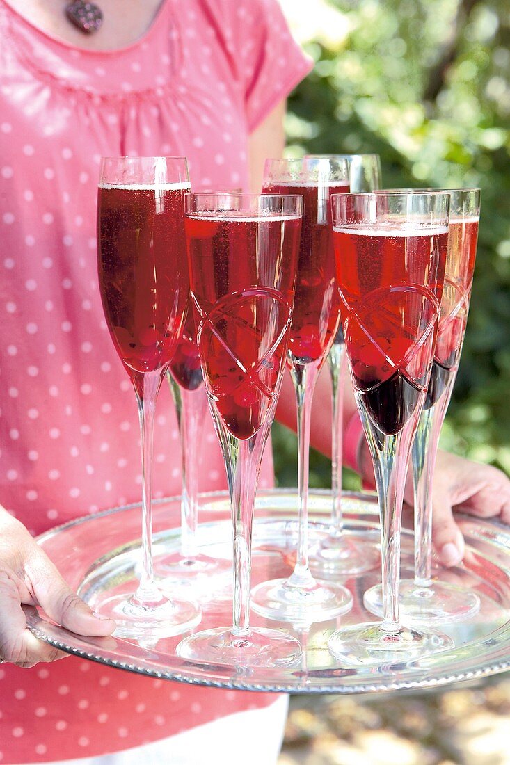 Woman holding tray of sparkling wine cocktails