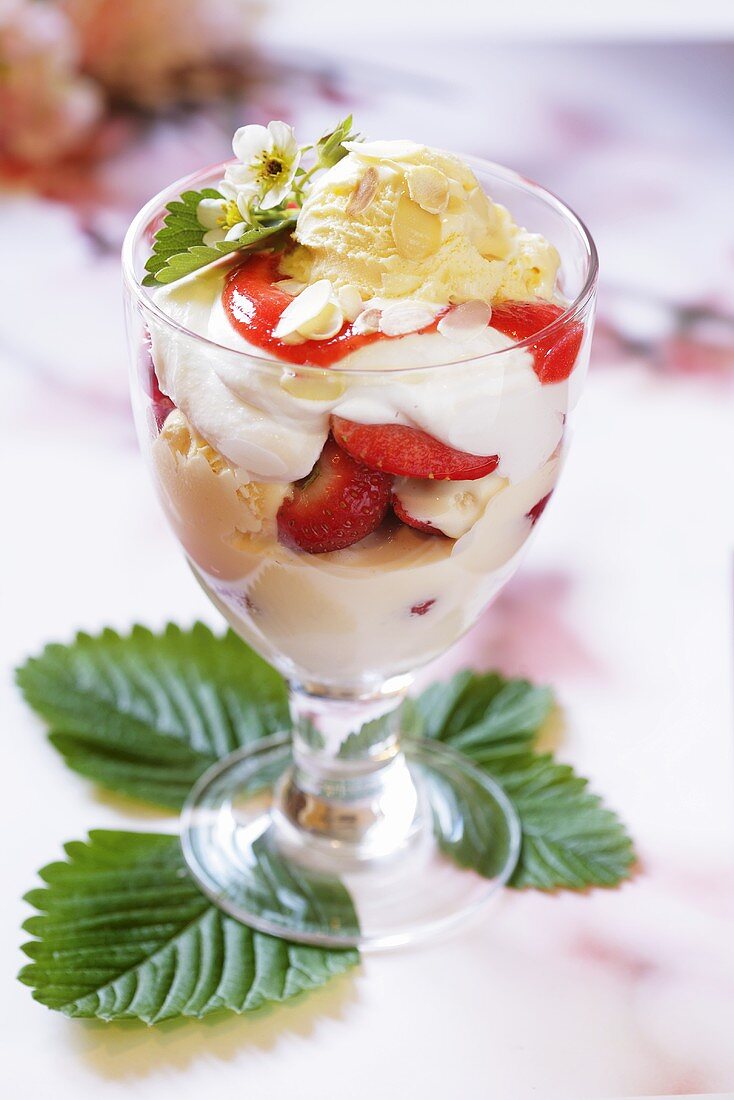 Eisbecher mit Erdbeeren, Sahne und Mandelblättchen