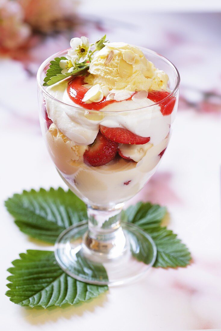 Ice cream sundae with strawberries, cream and flaked almonds