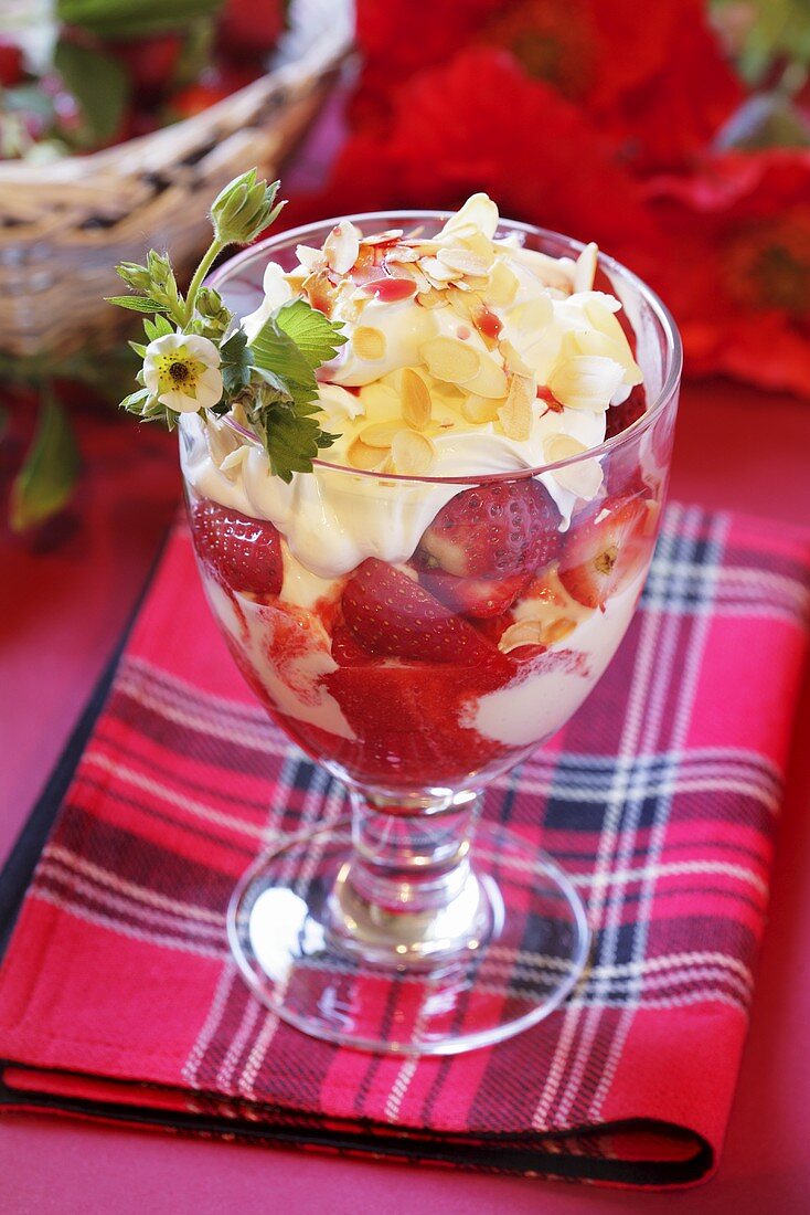 Eisbecher mit Erdbeeren, Sahne und Mandelblättchen
