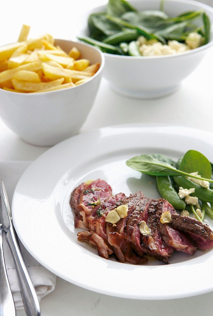 Gebratenes Steak in Scheiben, Pommes und Salat