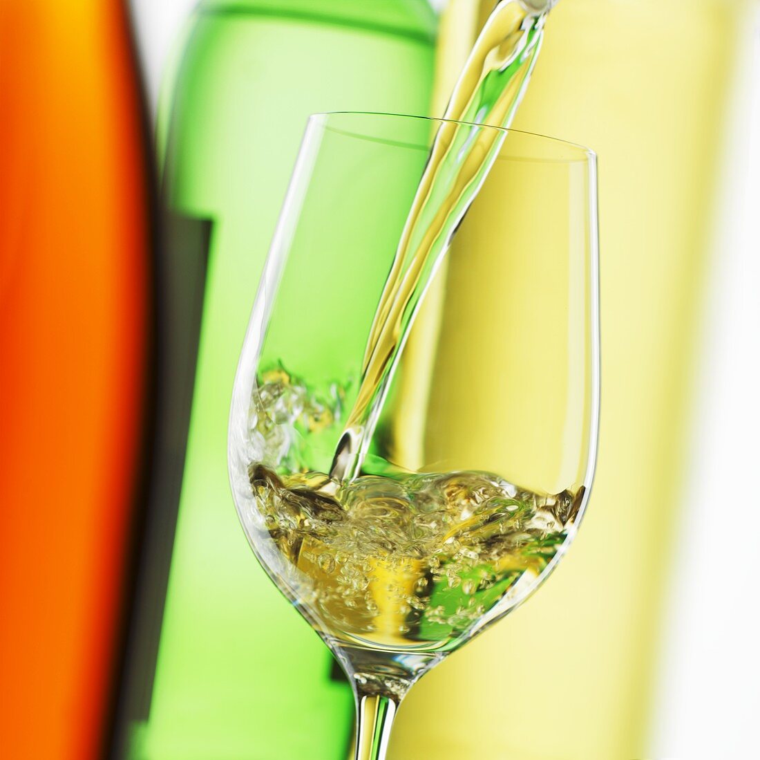 White Wine Pouring from Bottle into Glass; White Background 