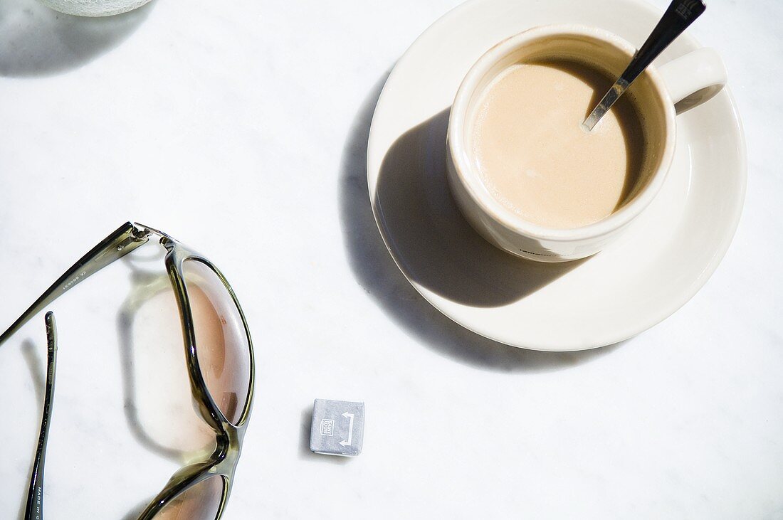 Milky coffee and sunglasses on table