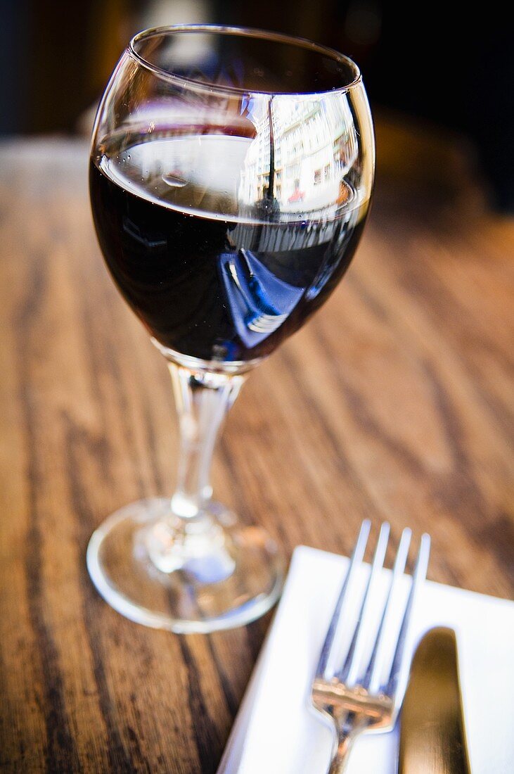 Rotwein im Glas auf Holztisch