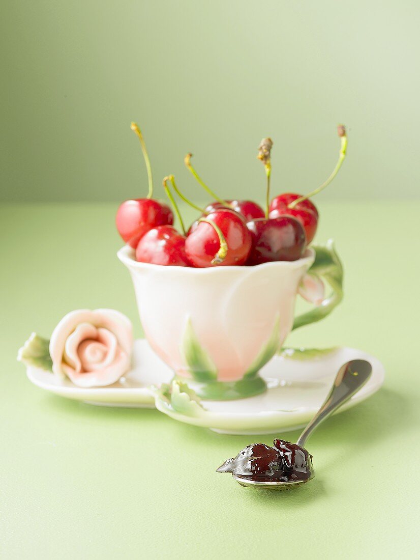 Kirschmarmelade auf Löffel, frische Kirschen in einer Tasse