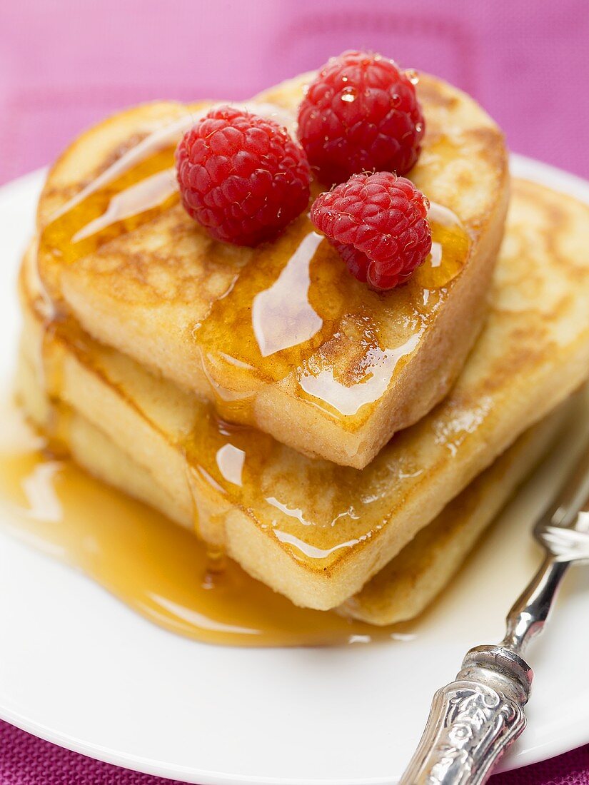 Herzförmige Pancakes mit Ahornsirup und Himbeeren