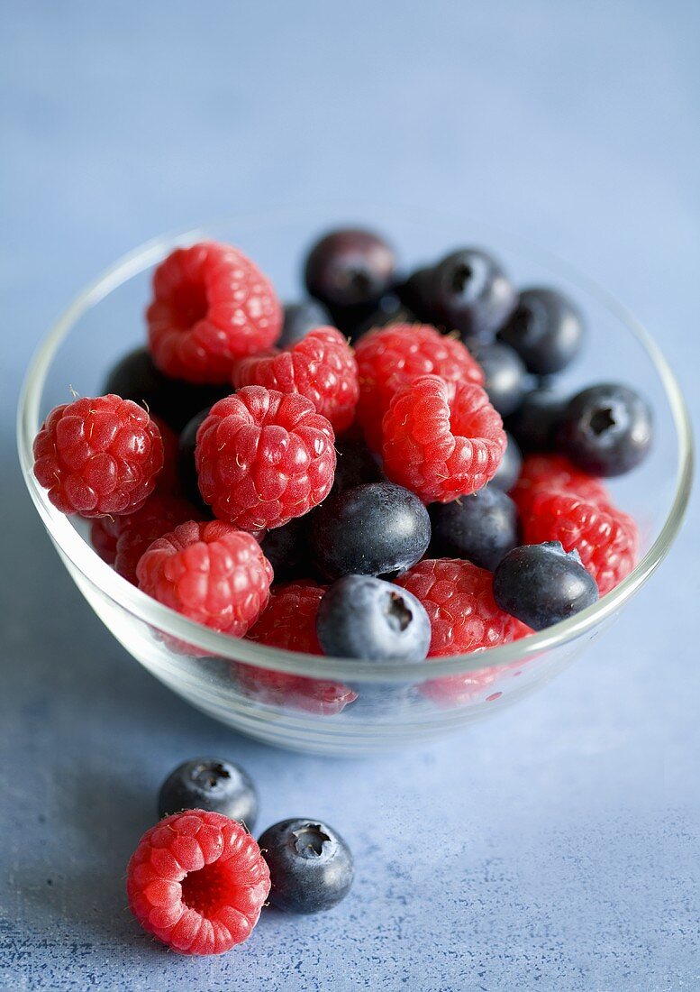 Raspberries and blueberries in glass bowl