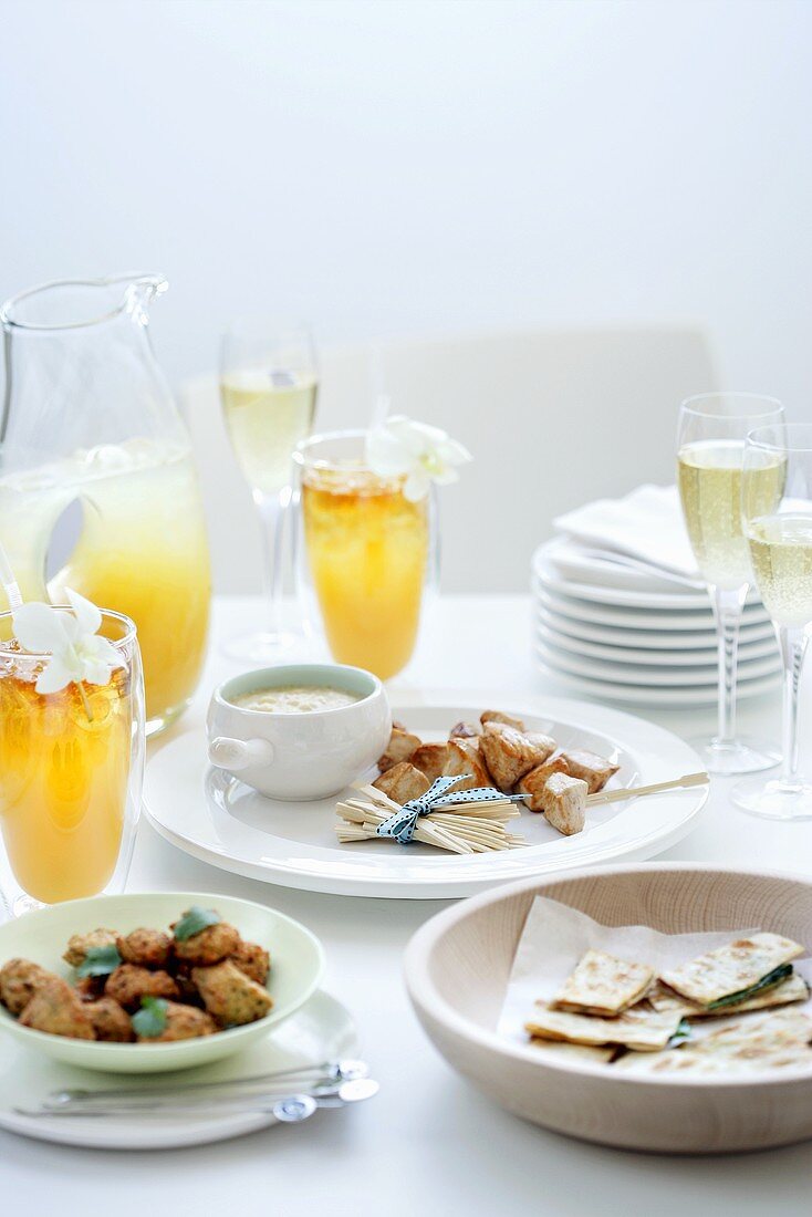 Party snacks, cocktails and sparkling wine on laid table