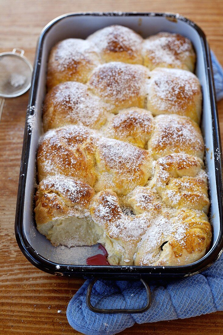 Rohrnudeln (sweet yeasted dumplings) with plums and icing sugar