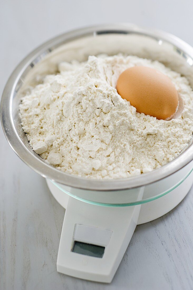 Mehl und Ei in Schüssel auf Küchenwaage