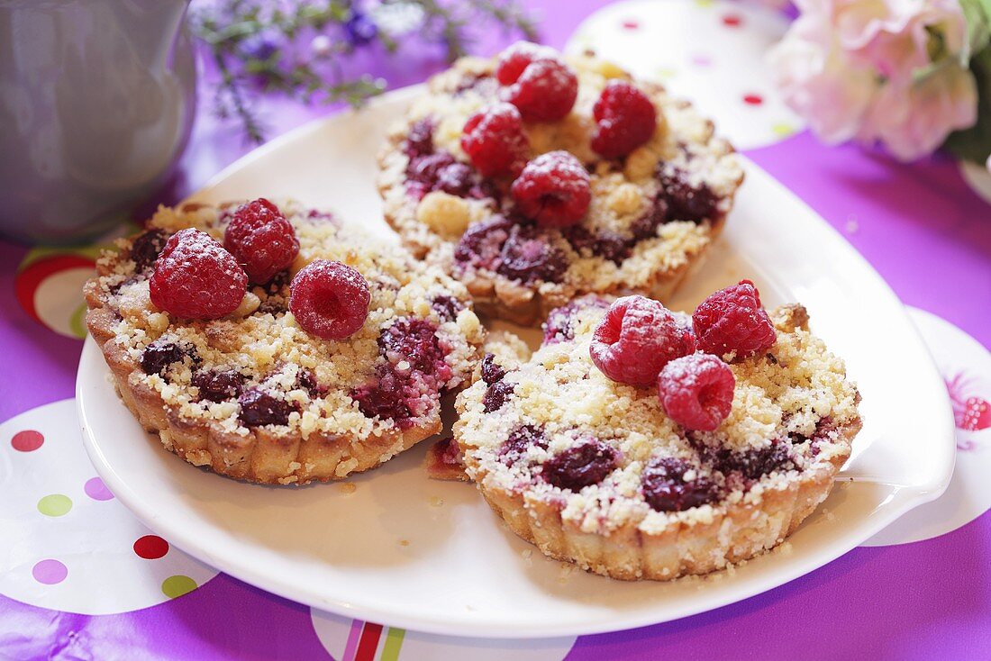 Fruit crumble tarts topped with fresh raspberries