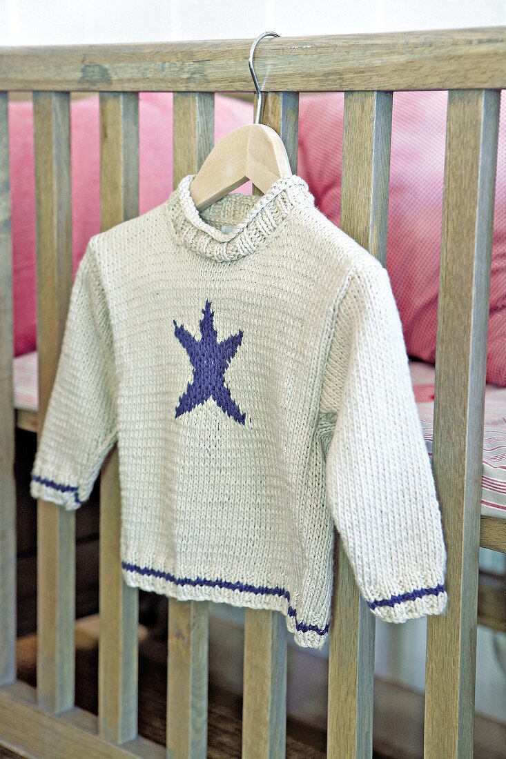 Gestrickter Kinderpullover am Kleiderbügel