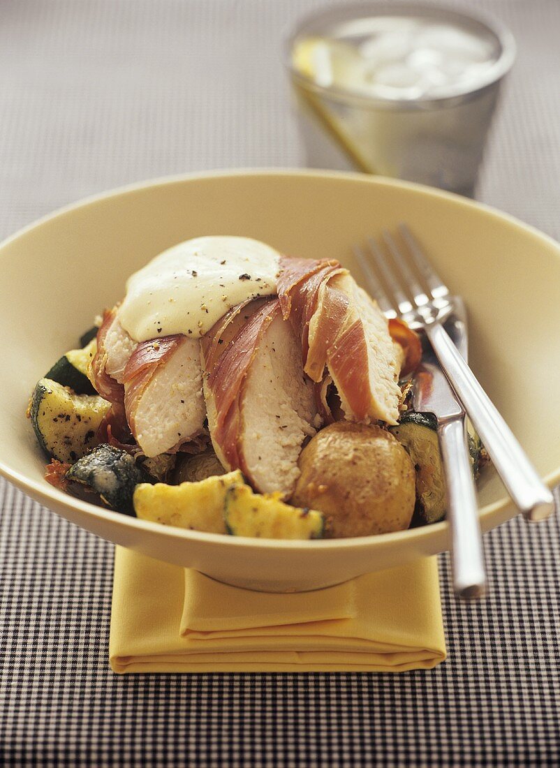 Chicken breast fillet wrapped in ham on vegetables