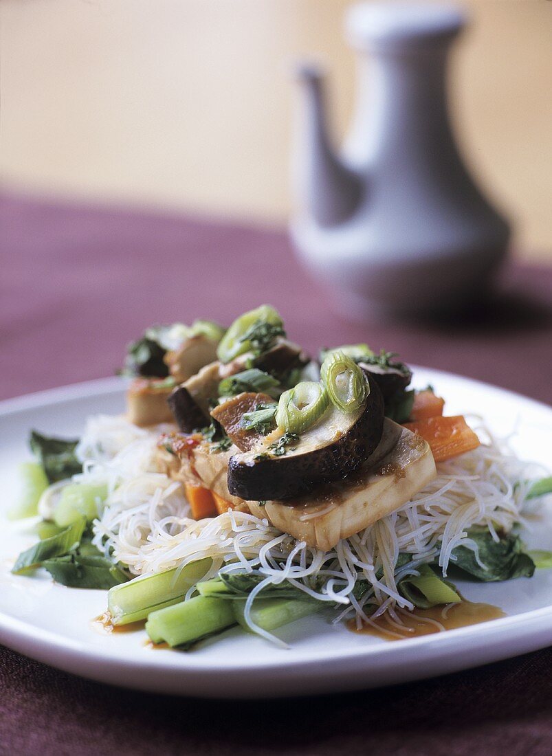 Slice of tofu on rice noodles with vegetables