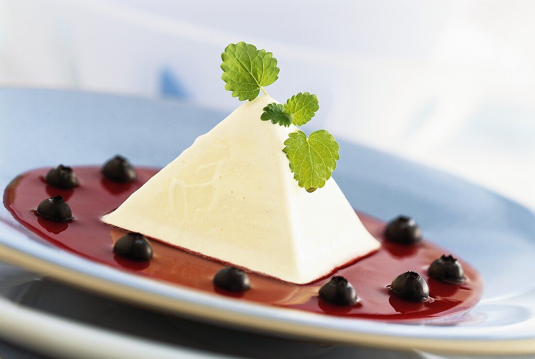 Pyramid-shaped cream dessert on hibiscus flower sauce