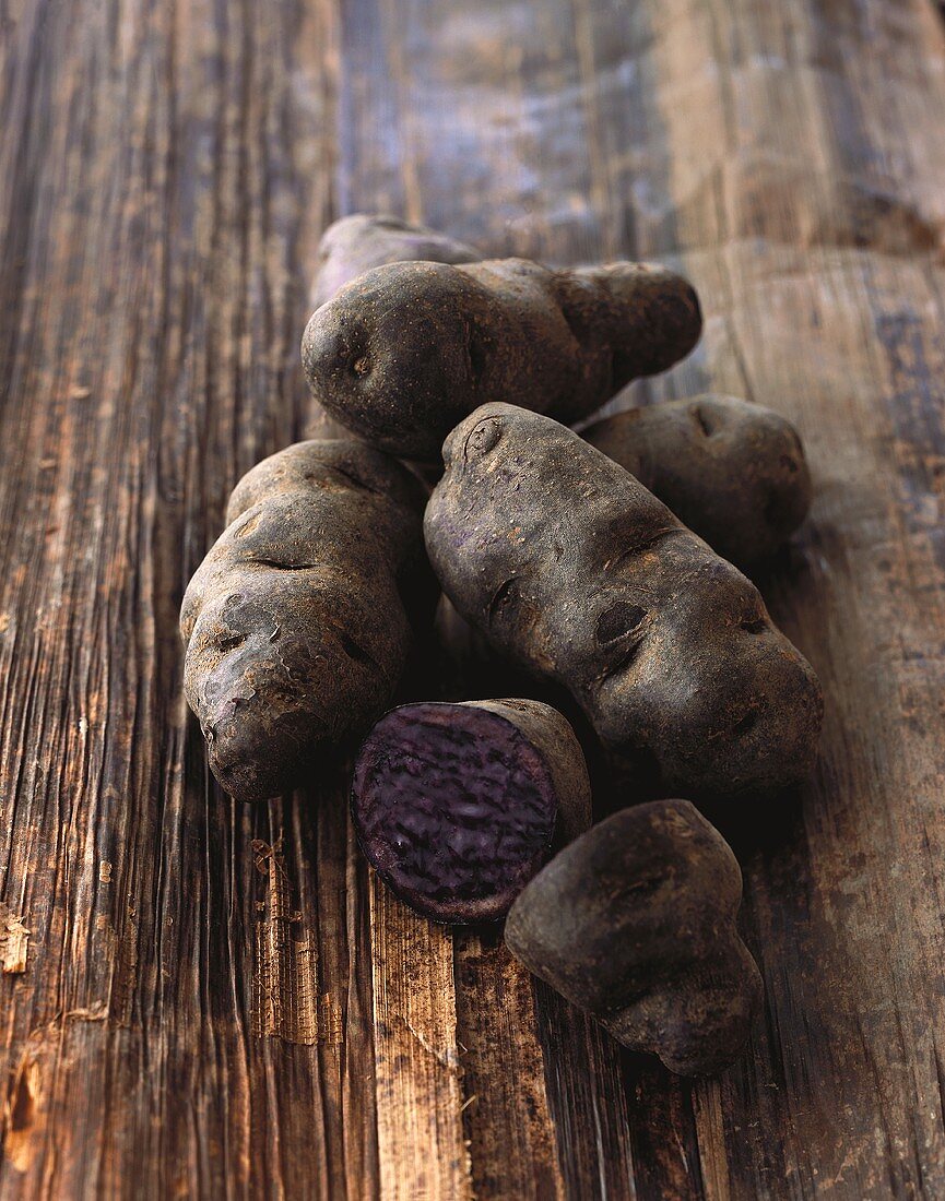 Purple potatoes (truffle potatoes) on wood