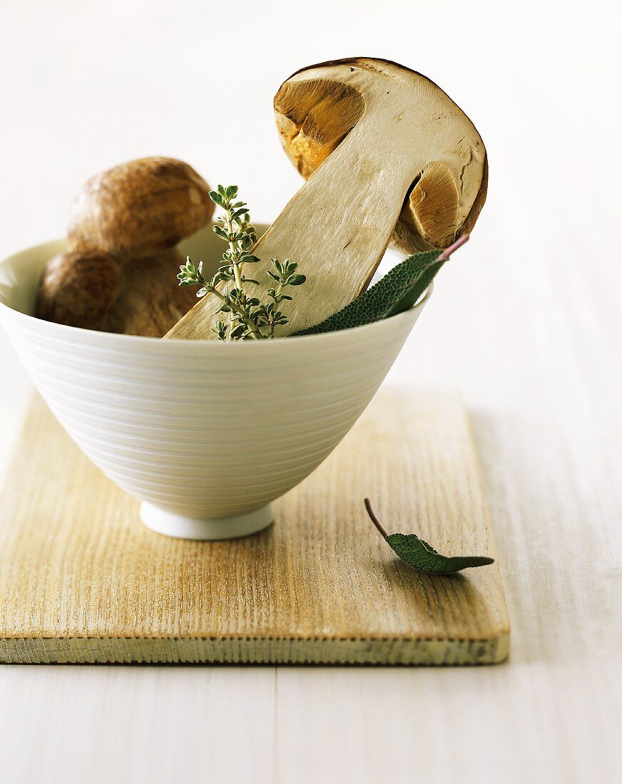 Halved cep with thyme and sage in a bowl