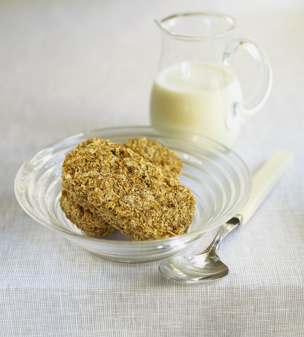Two wheat biscuits (Weetabix) in a bowl, milk behind
