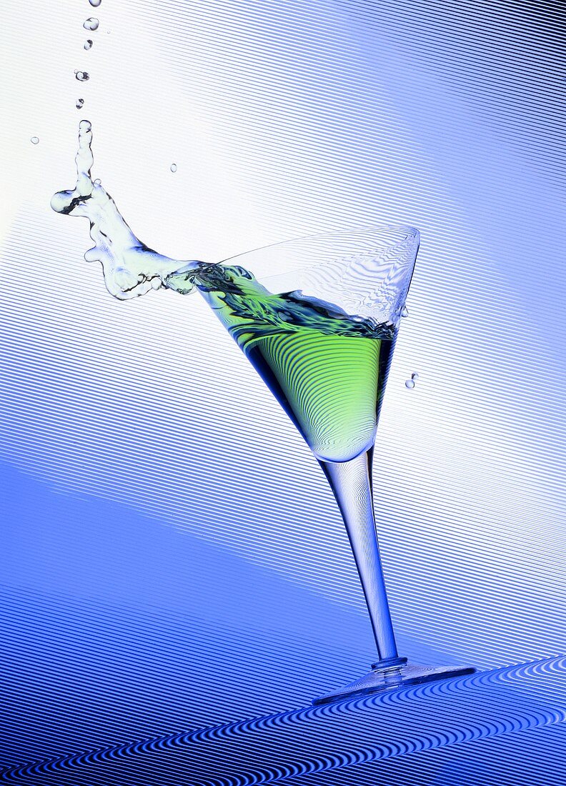 Green cocktail splashing out of a glass