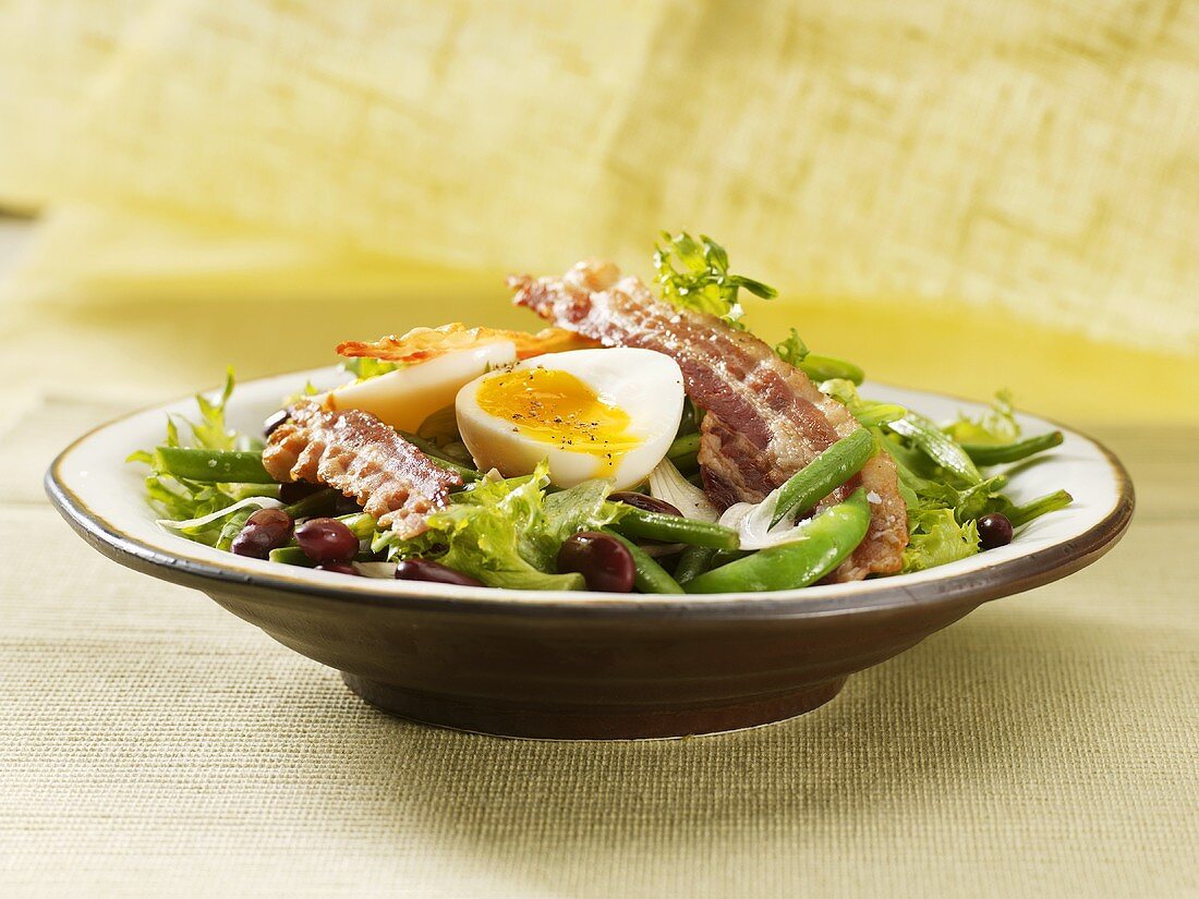 Salad with fried bacon and soft-boiled eggs