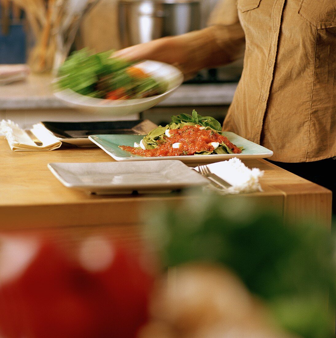 Salatschüssel zu Nudelgericht auf Tisch stellen
