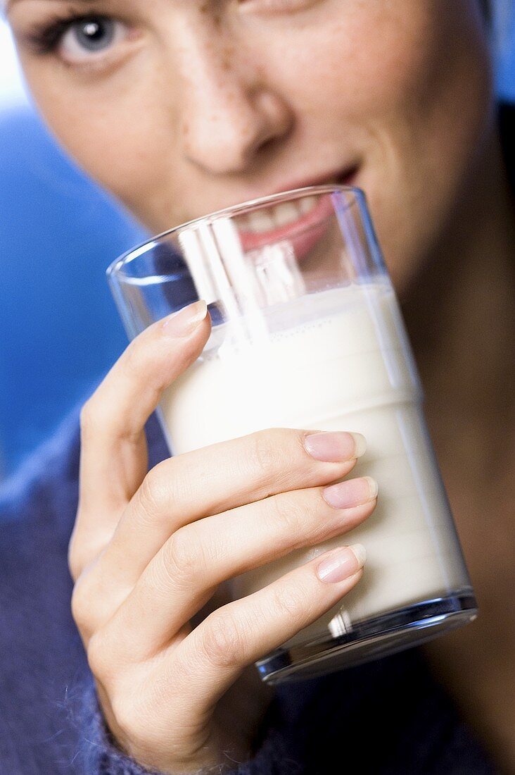 Junge Frau mit einem Milchglas vor dem Gesicht