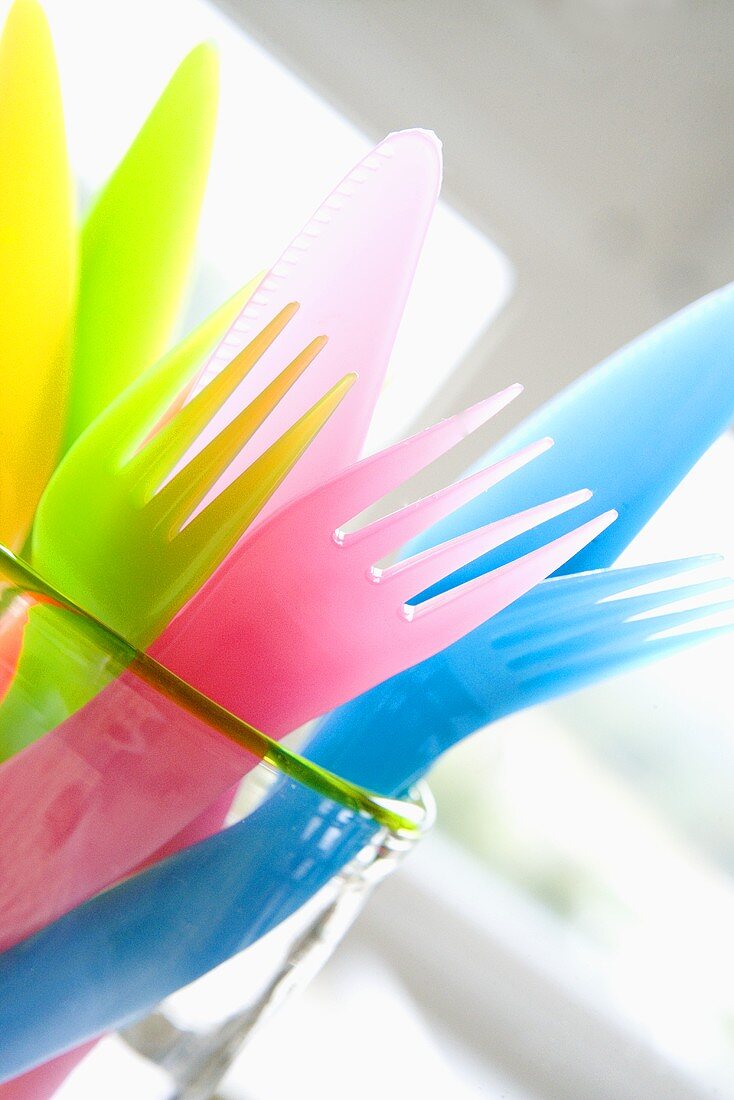 Coloured plastic cutlery in a glass