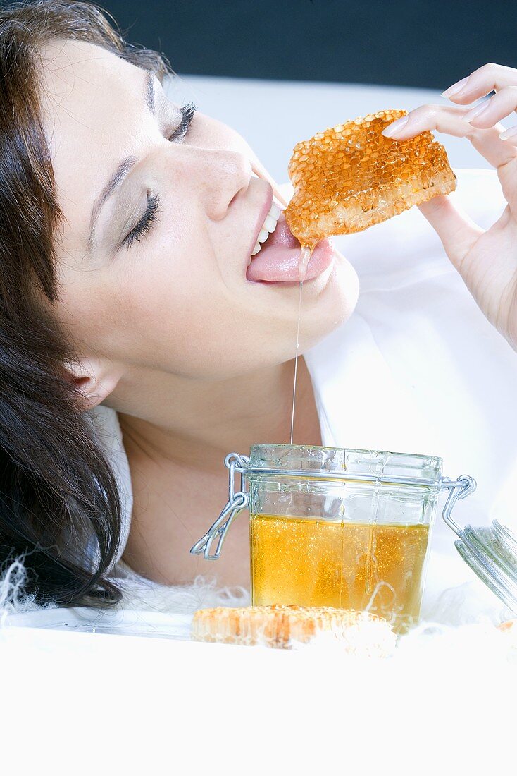 Young woman nibbling at a honeycomb