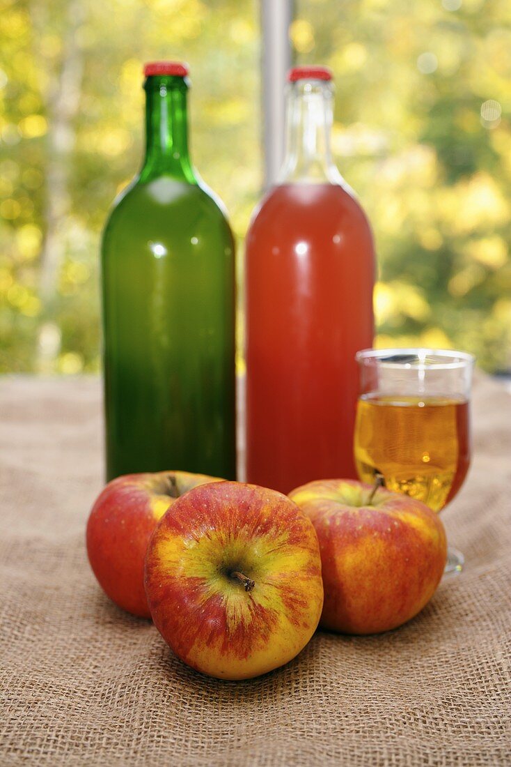 Bio-Apfelsaft, davor drei Äpfel