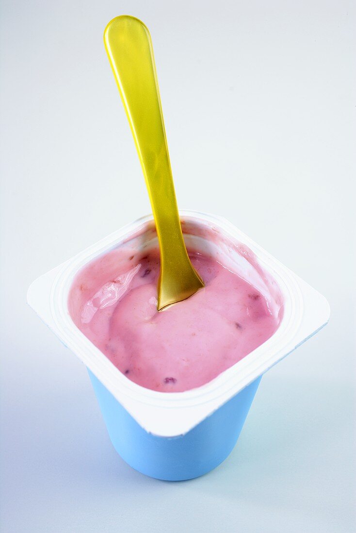 Strawberry yoghurt with yellow plastic spoon
