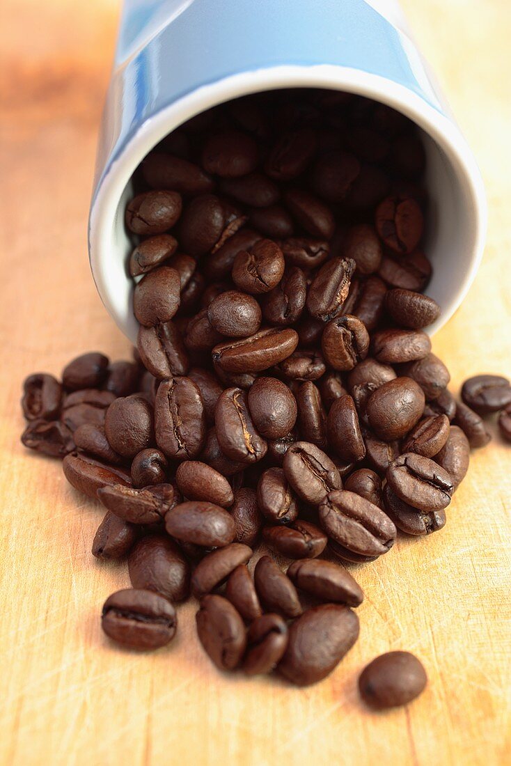 Geröstete Kaffeebohnen fallen aus Becher
