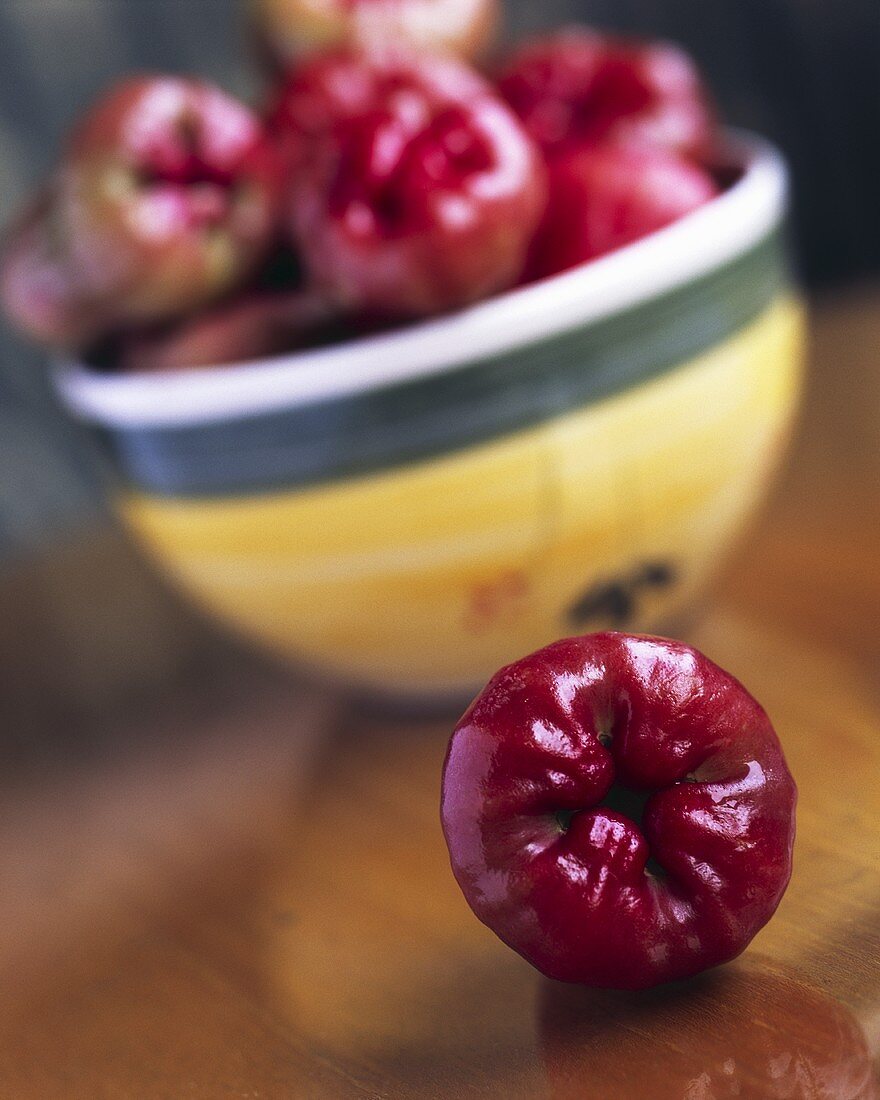 Rose apple in front of a bowl of rose apples