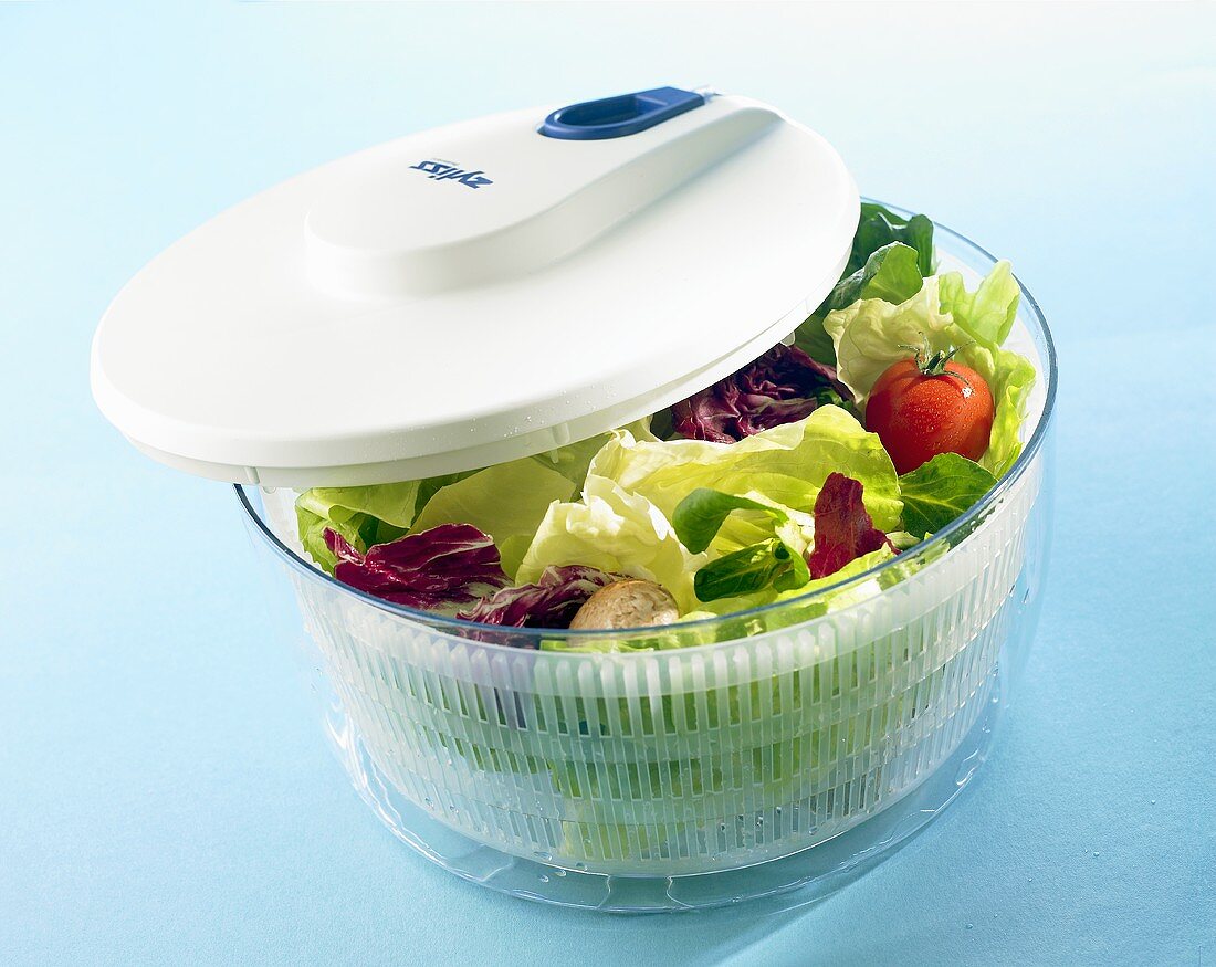 Salad spinner with salad leaves and vegetables