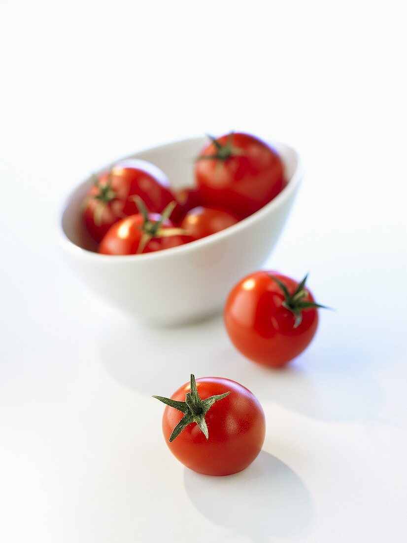 Zwei Tomaten vor einer Schüssel mit Tomaten