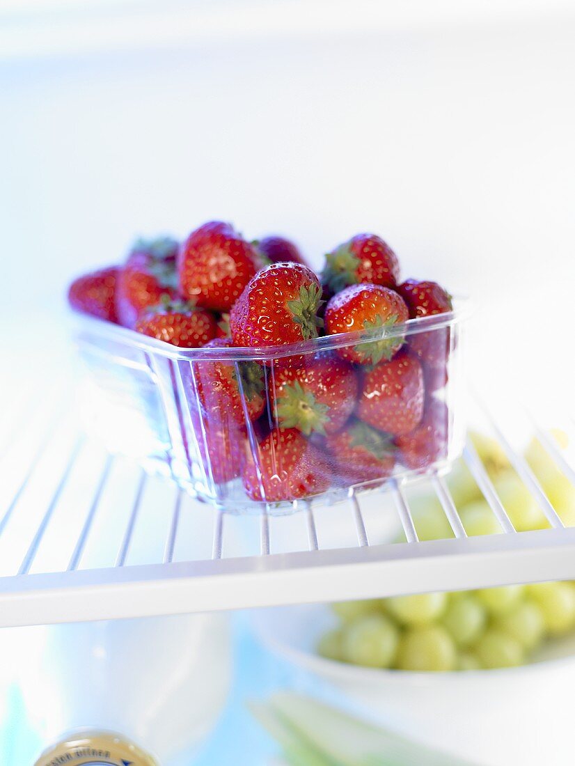 Erdbeeren in Plastikschale im Kühlschrank