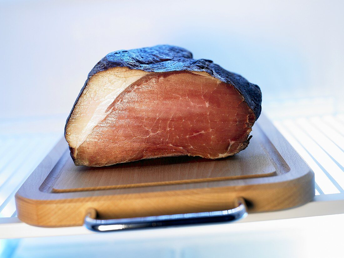Smoked ham on chopping board in fridge