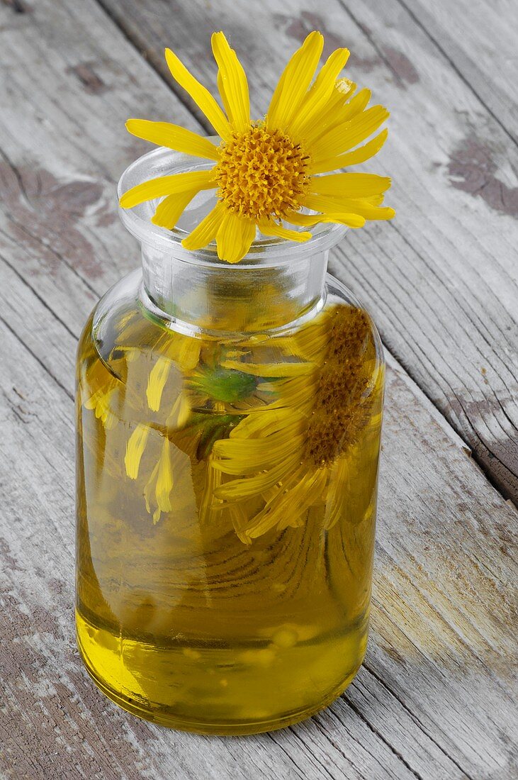 Arnikaessenz und Arnikablüten in einer Glasflasche