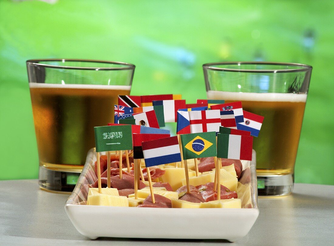 Ham and cheese on sticks with flags and beer in front of TV