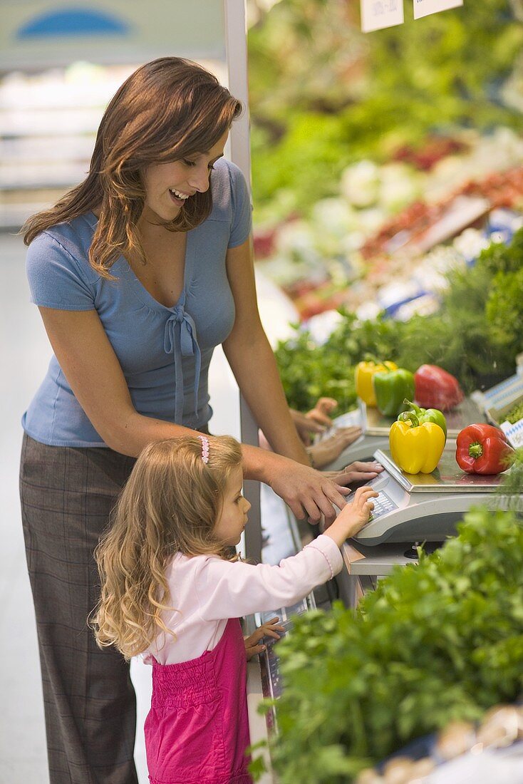 Mutter mit Tochter an einer Waage im Supermarkt
