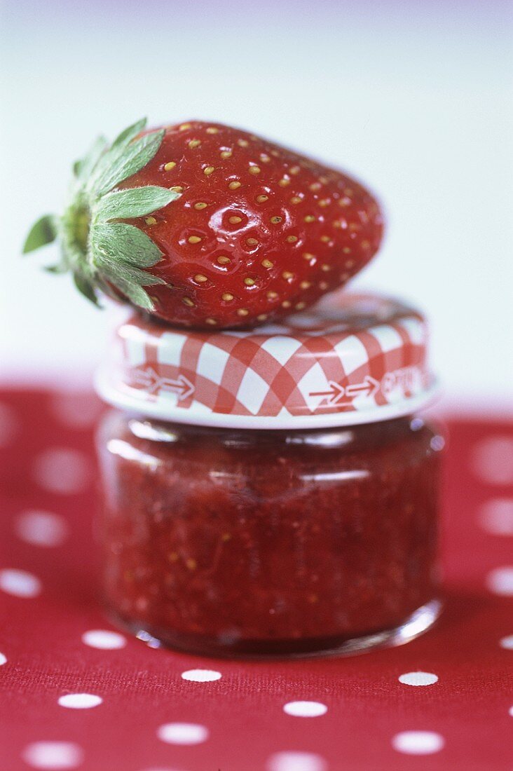 A strawberry on a full jam jar