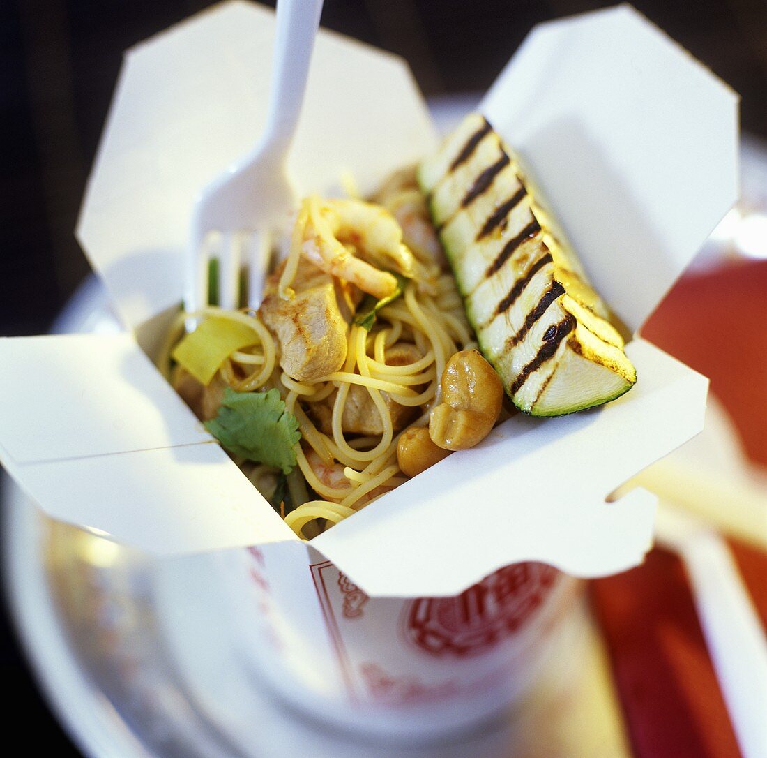 Pork with noodles and cashew nuts in take-away box