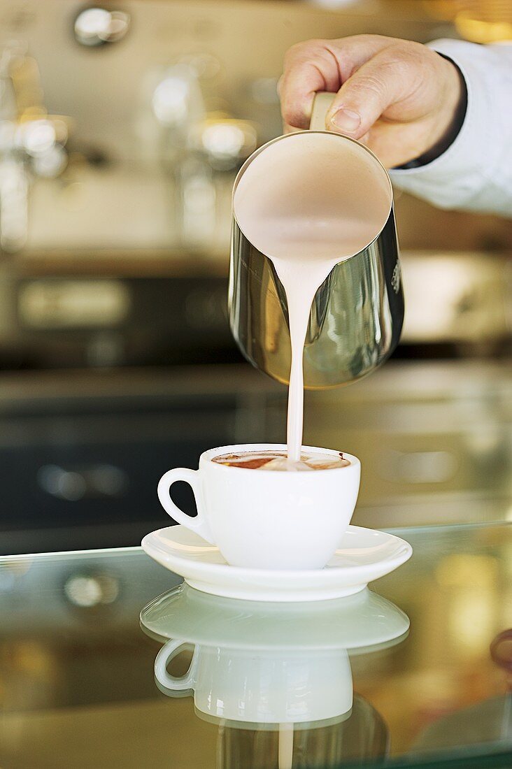 Einem Café Latte wird Milch zugefügt